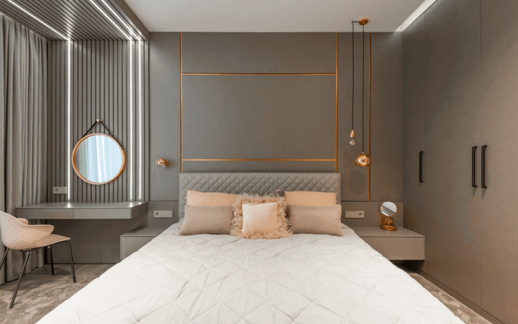 Une chambre à coucher avec des coussins de couleur pêche sur un fond marron clair et des accents métalliques dorés.