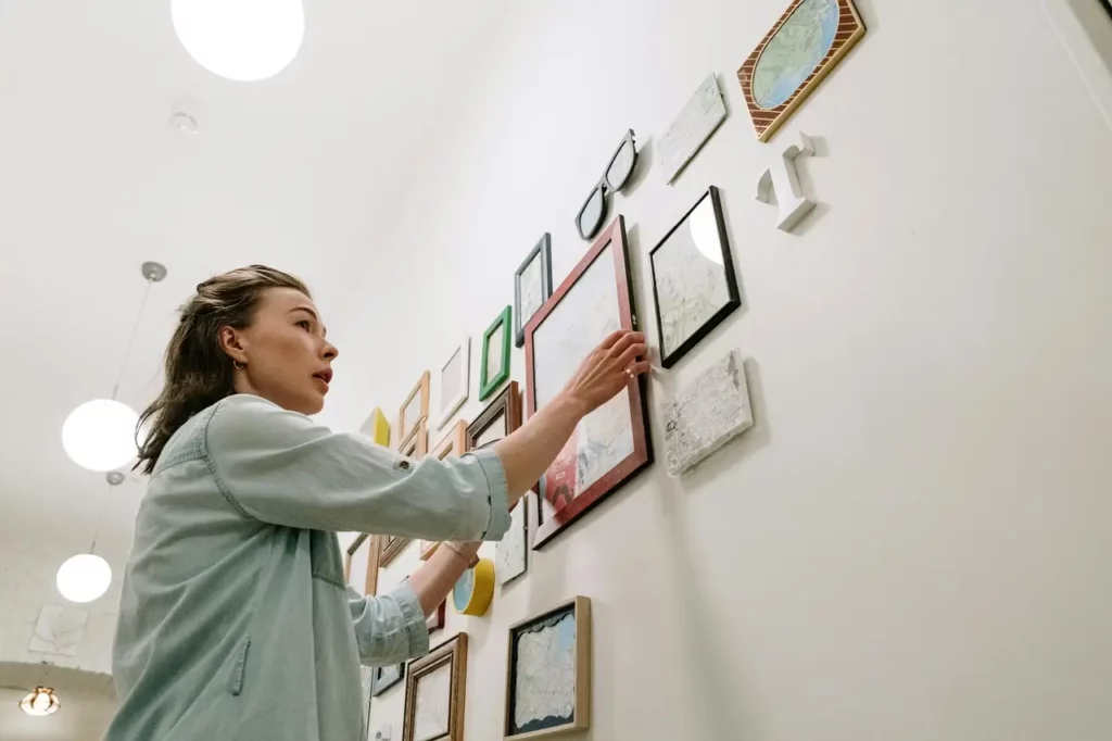 Femme accrochant des photos au mur pour créer une galerie murale