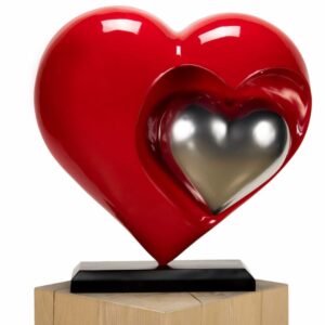 A modern red heart sculpture with an embedded silver heart element on a display stand.