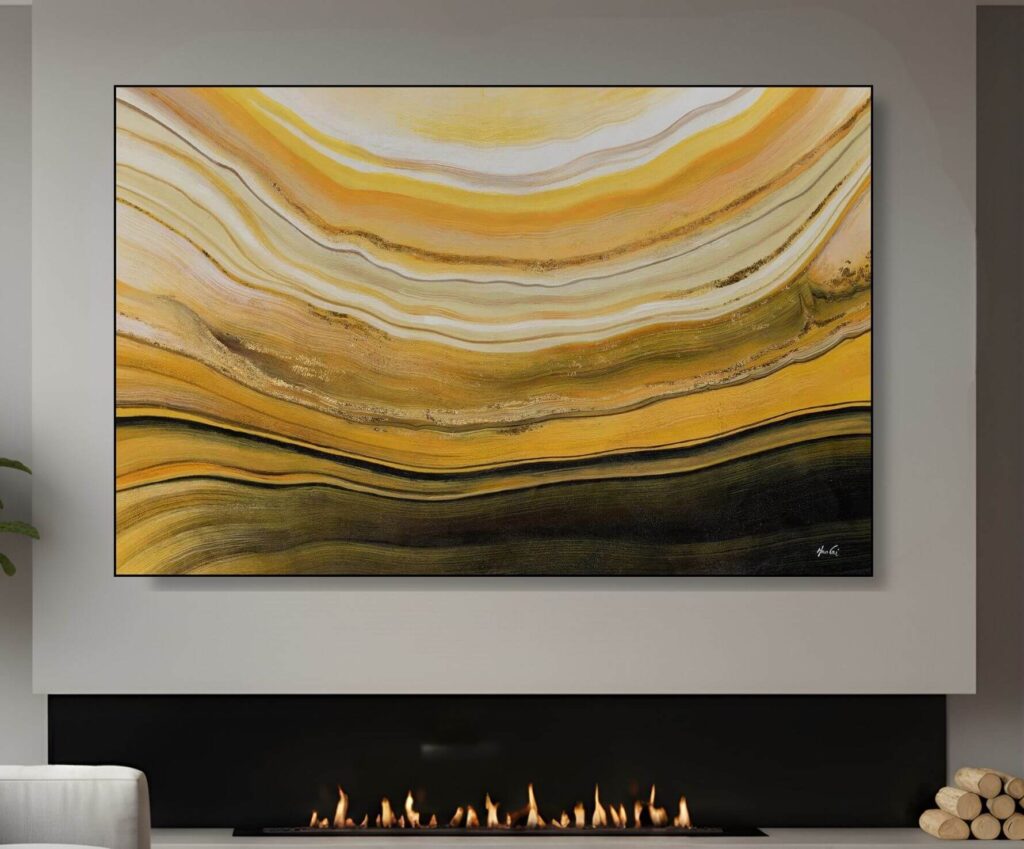 A wide horizontal abstract painting with wavy, topographical-like lines in shades of gold and ochre, hung above a modern fireplace.