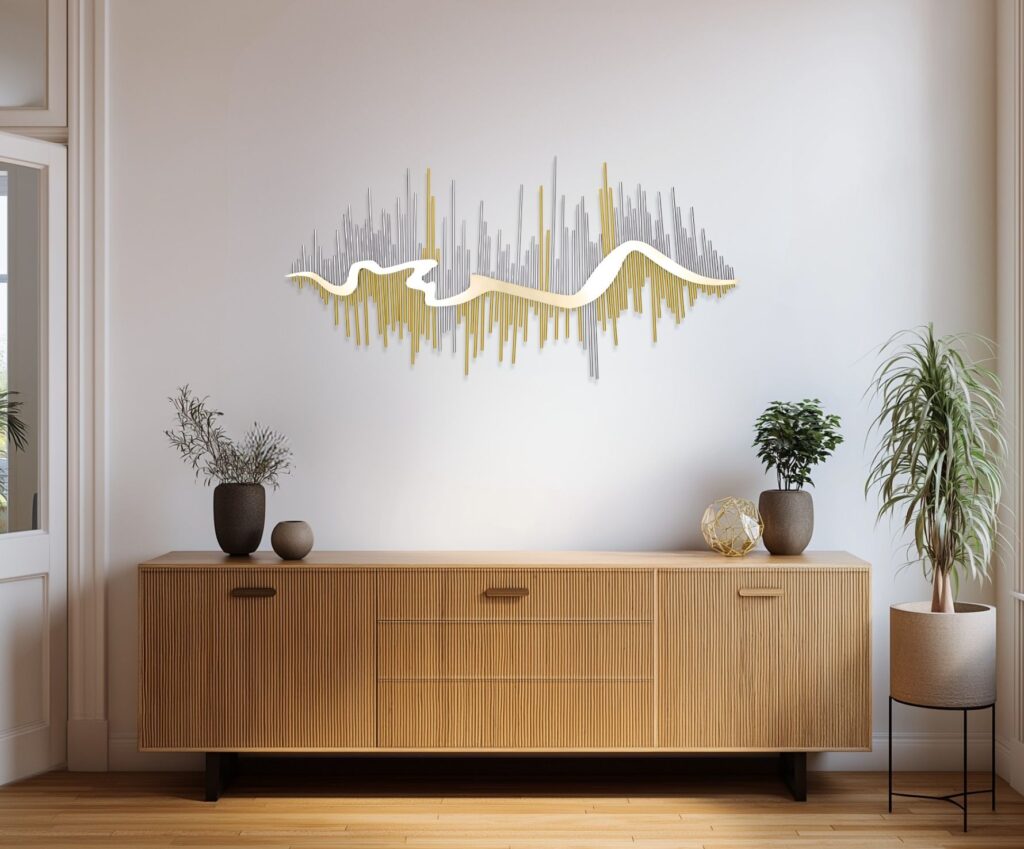 A wide landscape metal wall sculpture with fluid, organic gold and silver waves, mounted above a mid-century modern wooden sideboard.